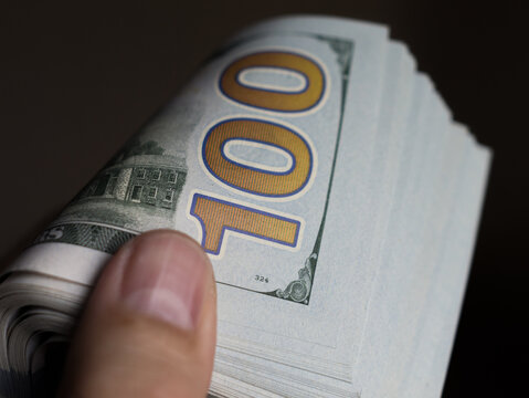 Close-Up of a Hand Holding a Stack of One Hundred Dollar Bills