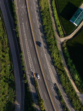 Aerial drone view of vehicle driving on green summer road. Transportation and logistics concept.