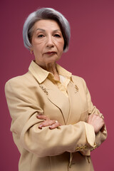 Fototapeta premium Elegant senior woman showcases timeless fashion and confidence in studio setting