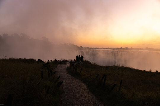 family taking smart phone pictures, Victoria Falls at sunrise from the Zimbabwe side