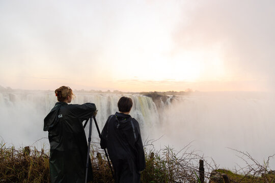 young woman and young brother looking at Victoria Falls at sunrise from the Zimbabwe side