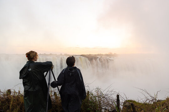 young woman and young brother looking at Victoria Falls at sunrise from the Zimbabwe side