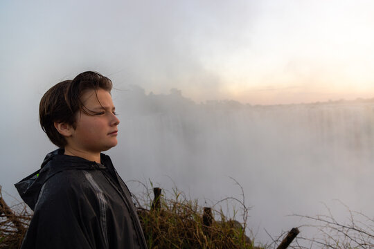 boy  looking at Victoria Falls at sunrise from the Zimbabwe side