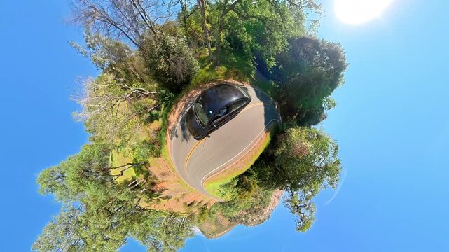 Tiny planet view of a car driving on a winding forest road in California, Creative spherical video captures a sunny journey through green woodland