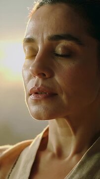 Vertical video: Breathing woman feeling golden light, doing slow breaths on balcony, wearing robe
