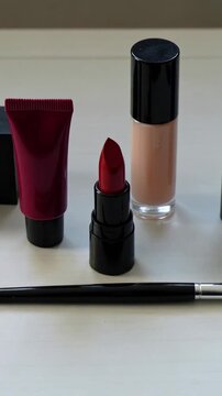 Vertical video: Entering right hand placing red lipstick sliding brush, tube, base on sill to show
