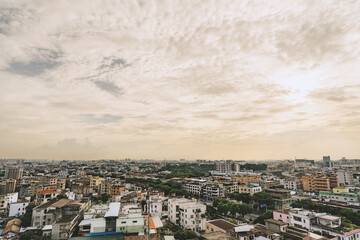 Obraz premium Aerial cityscape view of dense urban neighborhood under expansive cloudy sky with soft golden light at dusk