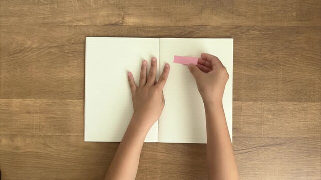 Child Peels Off a Pink Sticky Note from a Notebook, 4K