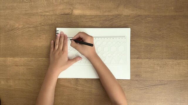 Child Draws a Circle on a Sketchbook Using a Shape Template with a Black Pen, Guided by an Adult Hand, 4K