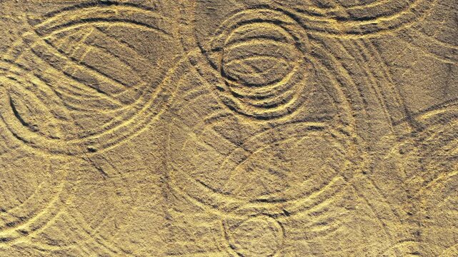 Abstract tire tracks on the sandy ground of Xinjiang, China, captured from an overhead perspective.