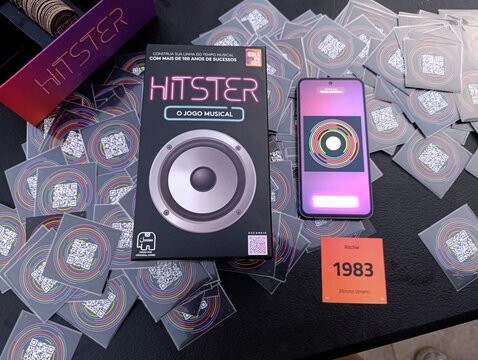 Hitster - Jogo de cartas e m&uacute;sica. O objetivo &eacute; simples: voc&ecirc; n&atilde;o precisa ser um especialista em m&uacute;sica, basta reconhecer os sucessos e organiz&aacute;-los em uma linha do tempo cronol&oacute;gica.