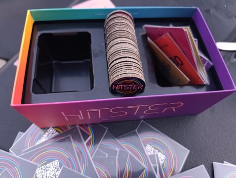 Hitster - Jogo de cartas e m&uacute;sica. O objetivo &eacute; simples: voc&ecirc; n&atilde;o precisa ser um especialista em m&uacute;sica, basta reconhecer os sucessos e organiz&aacute;-los em uma linha do tempo cronol&oacute;gica.