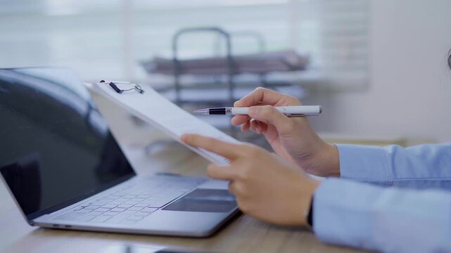 Close-up of Asian businesswoman using mobile phone, texting and cheating on her smartphone while outside office.