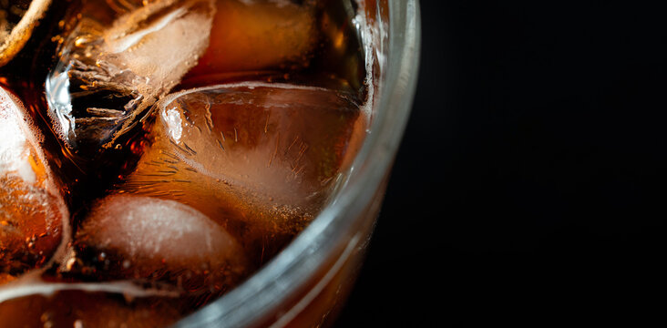 Extreme macro close up of cola soft drink with ice cubes and sparkling carbonation creating refreshing beverage texture with copy space. 