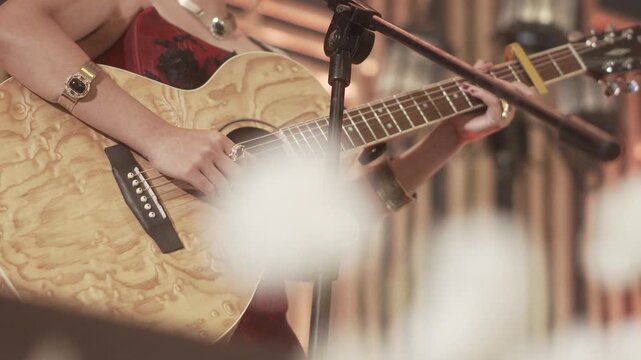 Female guitarist performing with an acoustic guitar, creating a warm and intimate atmosphere at a live music event.
