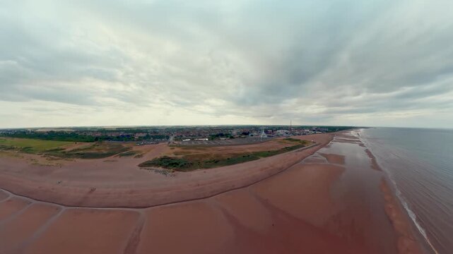 Aerial view of a sweeping, reddish-brown beach under overcast skies