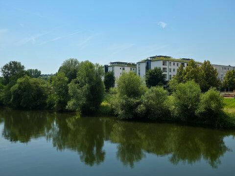 germany, modern riverside homes behind lush tree lined neckar river creating fresh urban nature harmony in plochingen summer landscape