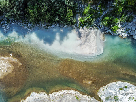 Sewage discharge flowing into a clean river aerial drone view. Wastewater entering river. Pollution from sewage pipe flowing into clean river from above.