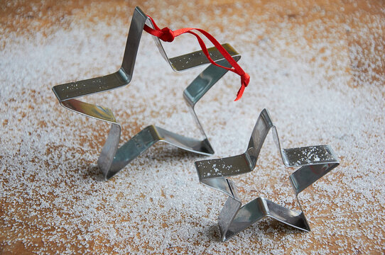 Close-up of two Christmas metal Star shaped cookie cutters on a table covered in sugar