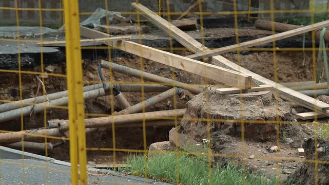 construction site where excavation is taking place. Wooden barricades and pipes are present, indicating active construction