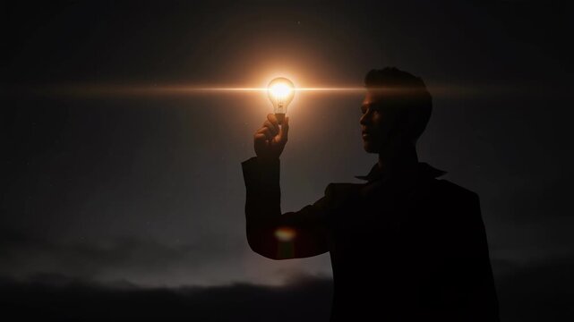 Silhouette of man holding glowing light bulb representing creativity and innovation in dark background