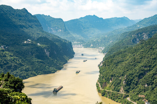 Cargo ships travel along the Yangtze River through the scenic Three Gorges Reservoir near Yichang in China on a bright sunny day