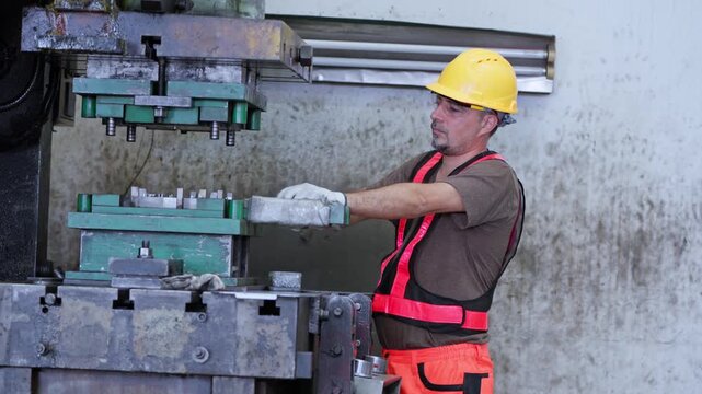 A factory worker skillfully managing heavy equipment while wearing essential safety gear in a manufacturing setting