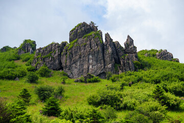 Rugged rocky peaks rise above the lush green grass and dense vegetation in the scenic Shennongjia Forestry District located in the Hubei province of China © AS_SleepingPanda