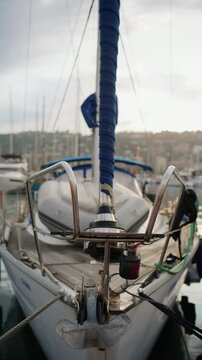 Close up view of a sailboat stern with blue wrapped rigging, anchor, deck hardware, and marina reflections at Port Vauban in Antibes, France