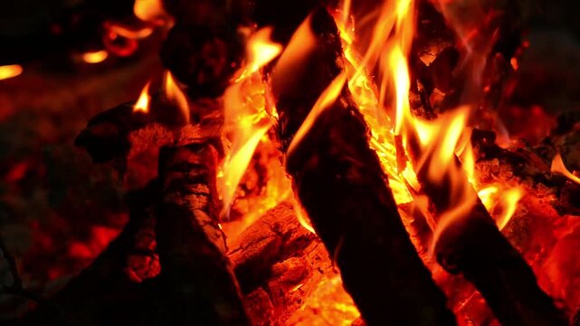 Extreme close up of burning wood logs and glowing red embers in a campfire, seamless loop animation with real sound of crackling fire, warm textures for relaxing sleep background
