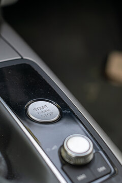 Close-up of a modern car start engine stop button on a sleek center console. Luxury vehicle interior panel, automotive ignition system, and smart keyless technology concept.