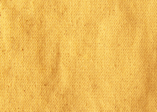 Close up golden bright yellow cotton linen canvas texture with woven details. Natural coarse texture for design fabric background. Rough crumpled hessian burlap background.