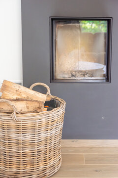 Contemporary fireplace design in a cozy home interior with a willow storage basket full of wood logs on a light laminate floor,Modern built-in square fireplace