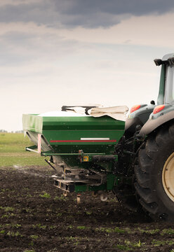 Tractor fertilizing field, Tractor spreading artificial fertilizers.