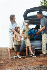 Happy, family and camping with car in nature for travel, roadtrip or outdoor holiday together. Children, mom and dad unpacking vehicle with gear for adventure, sightseeing or bonding in wilderness