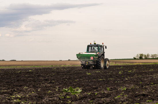 Tractor spreading artificial fertilizers in field
