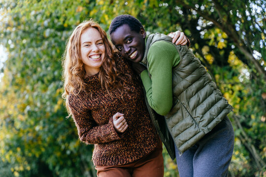 Happy diverse female friends embracing and smiling during relaxed autumn countryside walk