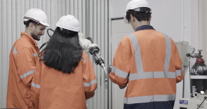 Female and Male engineers checking or maintenance electronic in AI or artificial intelligence robot arm in the manufacturing automation and robotics manufacture room. Service technical engineer. 