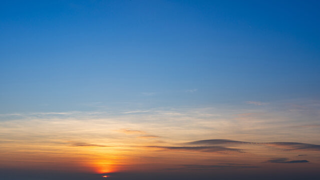 A vivid sunset sky transitions from deep blue to warm orange near the horizon, with wispy clouds