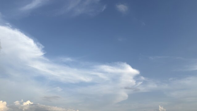 A clear blue sky featuring large white cloud formations during daylight