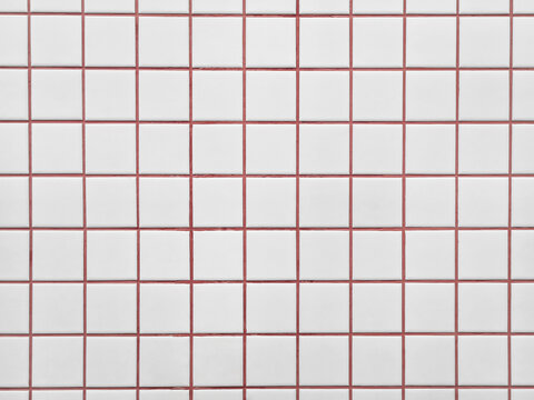 Background of minimalist white ceramic tile wall texture with bright red cement grout. Surface of white checkered tile pattern with red grout lines has modern Scandinavian for retro minimalist look.