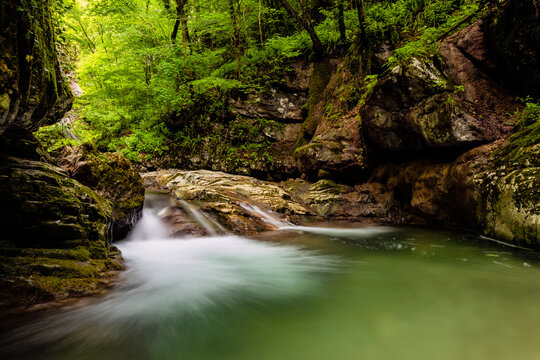 Mountain stream flowing over mossy rocks in a lush forest canyon, ideal for nature tourism and exploration, Sorna river, Rovereto, Vallagarina, Brentonico plateau, Trentino, Italy.