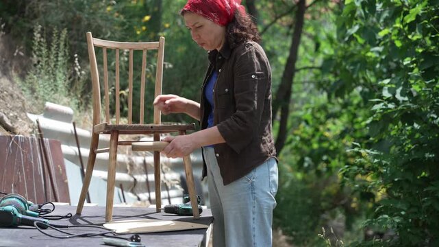 Woman restoring an old wooden chair by hand in a workshop, furniture restoration, craftsmanship and DIY renovation