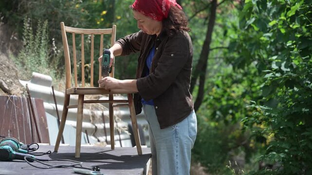 Female craftsperson restoring a worn wooden chair, antique furniture renovation, woodworking and sustainable reuse
