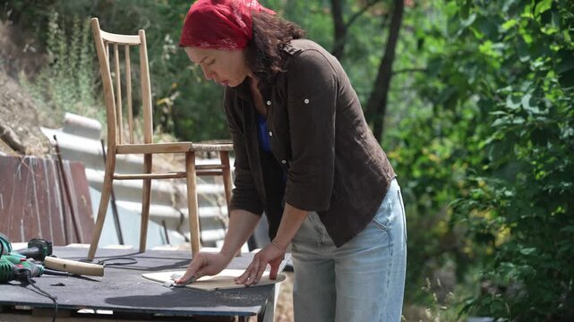 Woman restoring an old wooden chair by hand in a workshop, furniture restoration, craftsmanship and DIY renovation