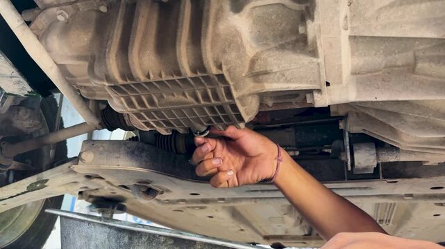 Mechanic Draining Manual Transmission Gear Oil During Routine Vehicle Maintenance Service