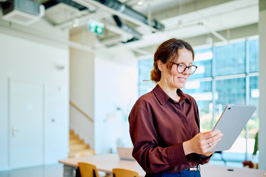 Young businesswoman smiling while working with a digital tablet, managing business with technology and communication