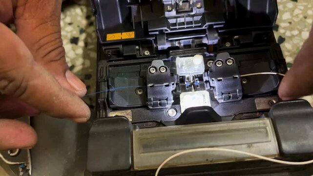 Technician Positioning Fiber Optic Cable In Fusion Splicing Machine For Network Repair