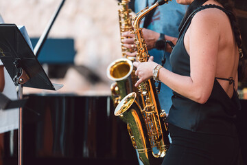 Fototapeta premium Female musician playing a saxophone with a band during an outdoor live performance