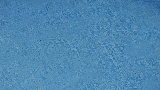 Top-down close view of textured blue pool interior surface with faint mottled finish, subtle shimmer, calm water look, clean commercial background for maintenance, renovation, and design use